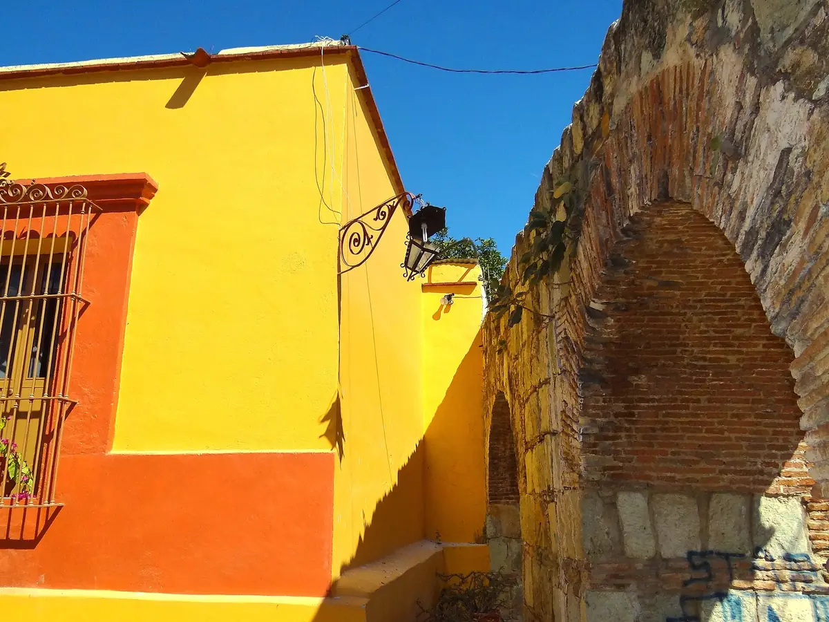 Muro amarillo y arco de piedra en Oaxaca